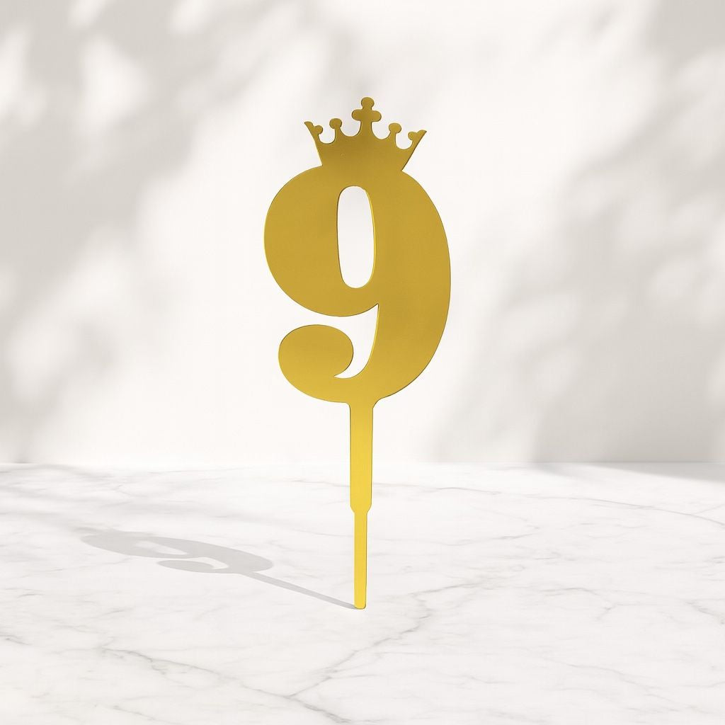 Gold number '9' cake topper with a crown on a white background