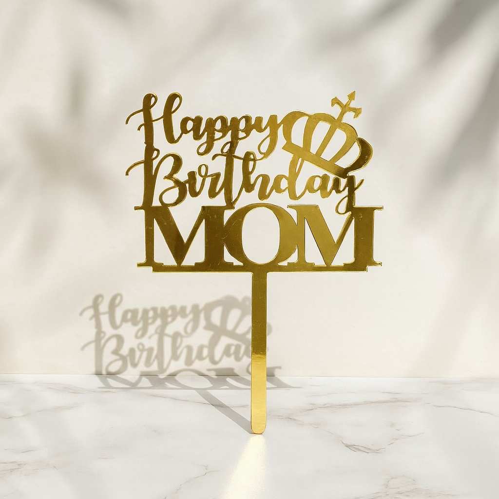 Gold 'Happy Birthday Mom' cake topper on a marble surface with a light background