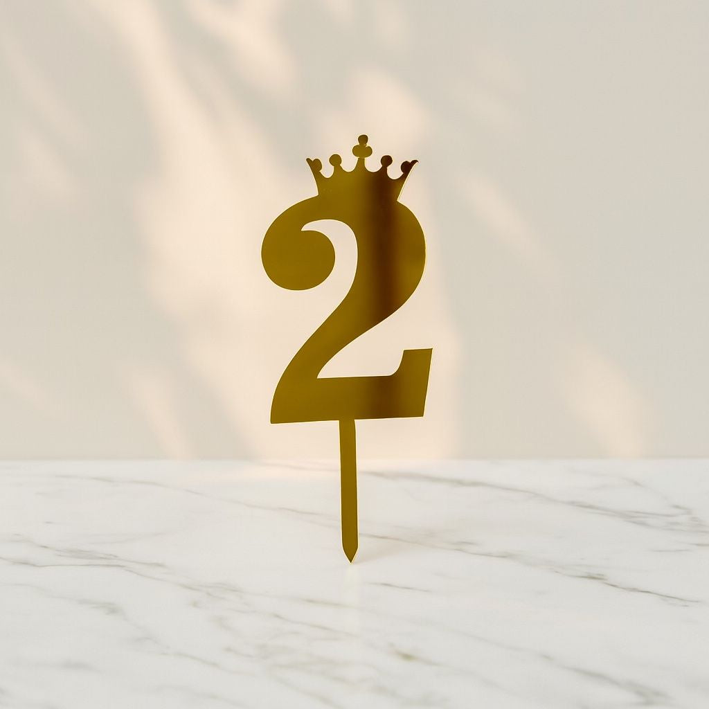 Gold number '2' with a crown on a white marble surface
