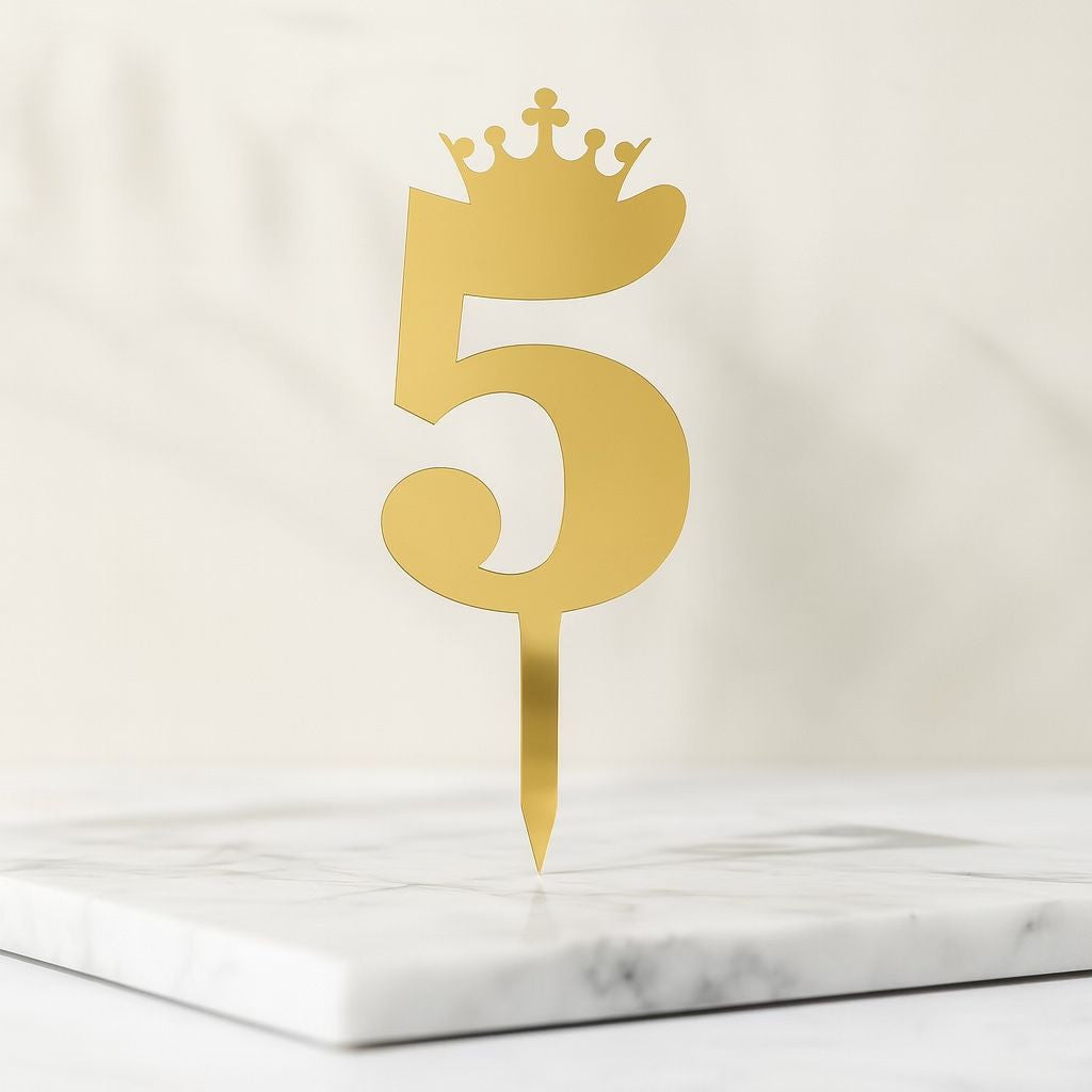 Gold number five with a crown on a marble surface