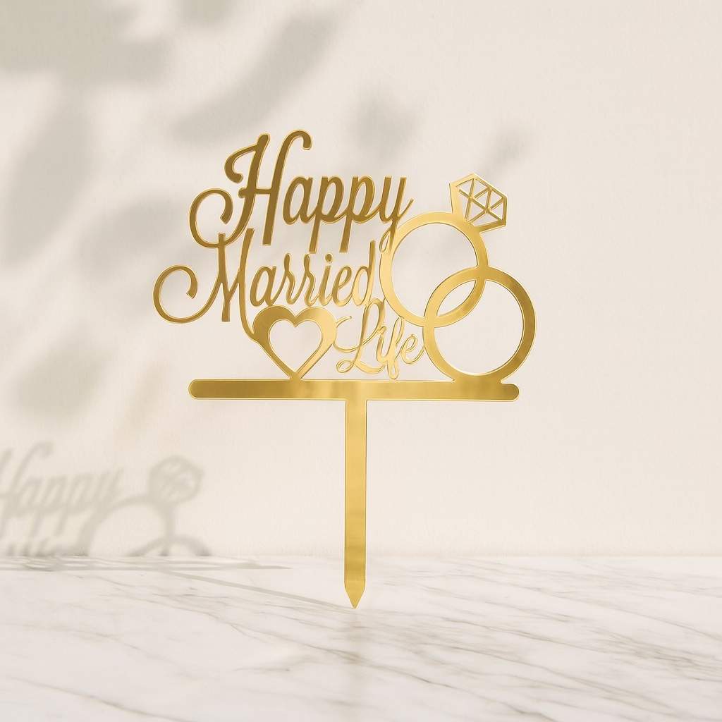 Gold cake topper with 'Happy Married Life' text and a ring design on a marble background