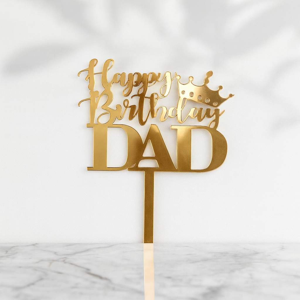 Gold 'Happy Birthday Dad' cake topper with a crown on a white marble background