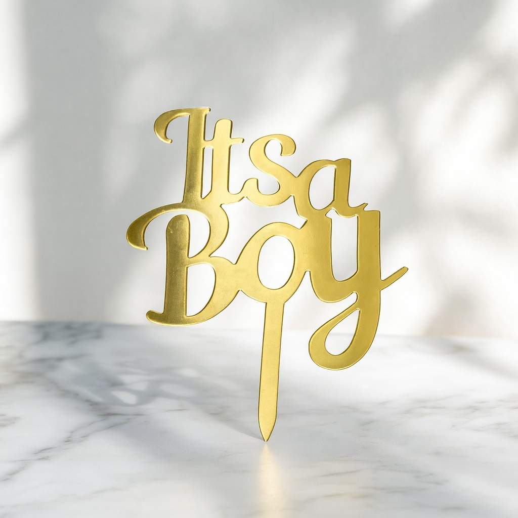 Gold 'It's a Boy' cake topper on a marble surface with a white background